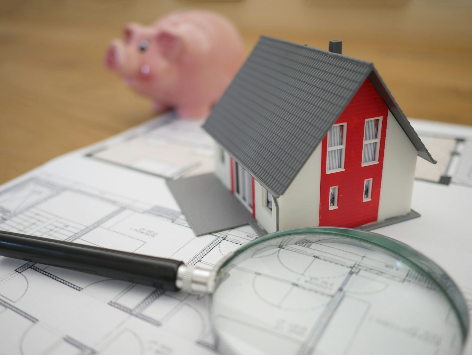 Model house on architectural plans with a magnifying glass